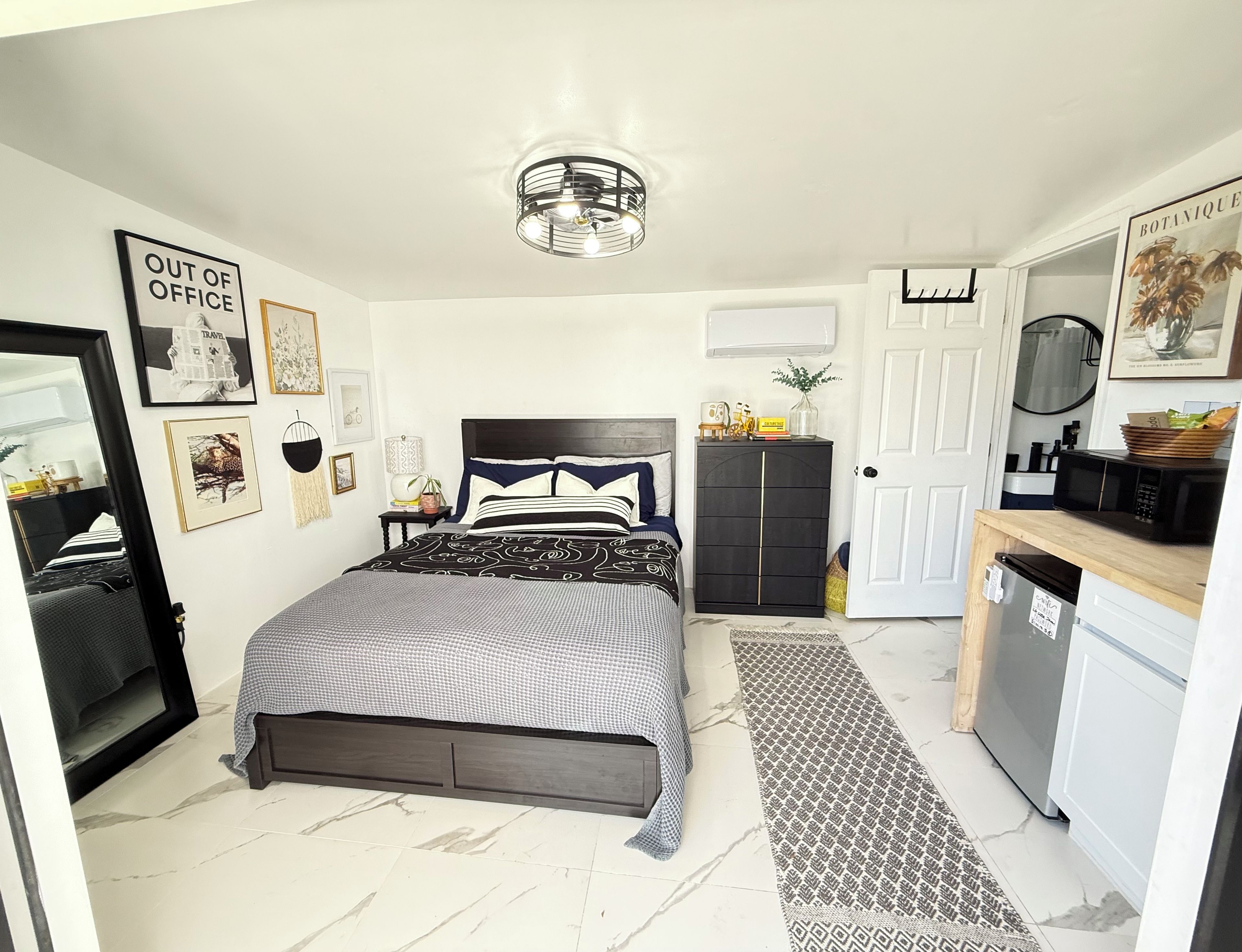 A bedroom with a bed, bedside tables, a wardrobe, a mirror, and a door.