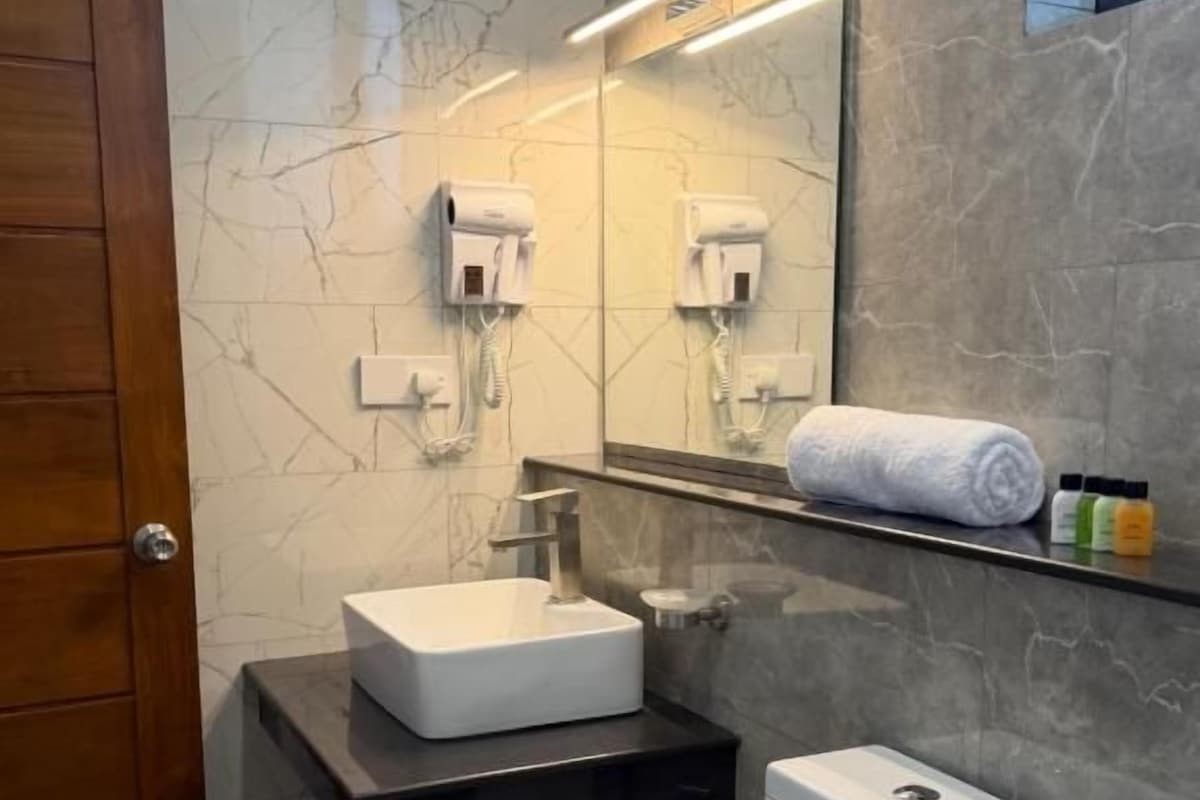 Un baño con un inodoro blanco, un lavamanos y un espejo.