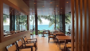 A restaurant with a view of the sea, featuring wooden tables and chairs, and a modern ceiling design. - Oceana Trinco (TRINCOMALEE)