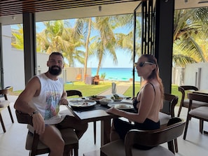 Un comedor con vista al océano y palmeras.