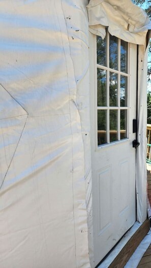 A white tent-like structure with a door and windows, suggesting a temporary accommodation setup.