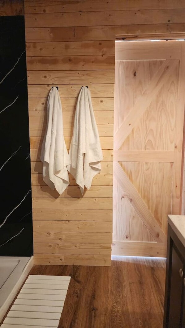 A wooden wall with two towels hanging, a wooden door, and a white floor.