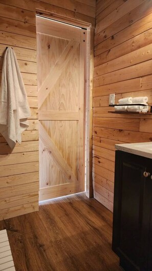 A wooden interior with a door, a towel hanging, and a cabinet.
