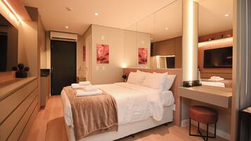 Quarto de hotel moderno com uma cama grande, mesa de cabeceira e televisão.