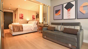 A hotel room with a bed, a sofa, and a desk. There are framed pictures on the wall. - Oscar by Bhomy (São Paulo)