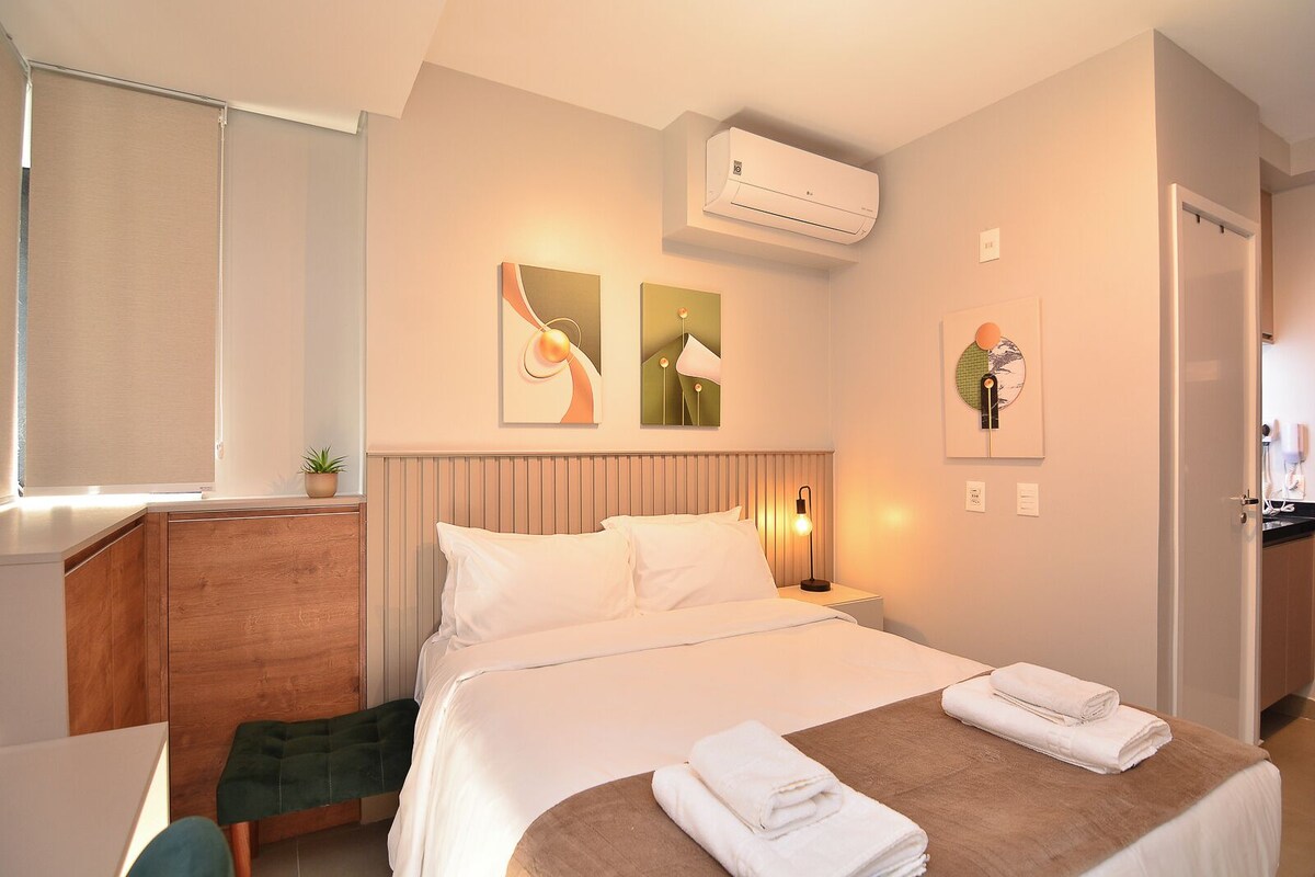Ein Hotelzimmer mit Bett, Nachttischen, Schreibtisch und Klimaanlage.