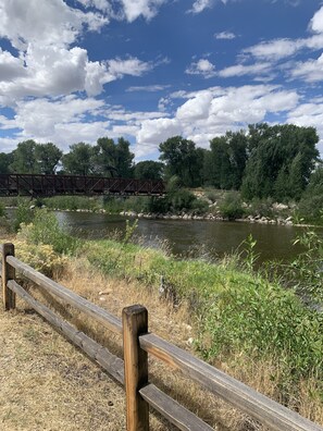 Una cerca de madera, un río y un puente en un entorno natural.