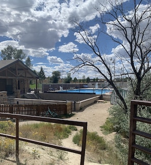 A pool area with a wooden deck, a stone building, and a fenced yard.