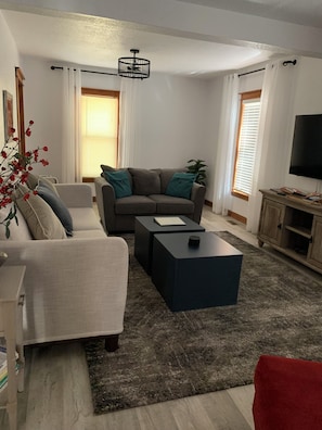Una sala de estar con un sofá, una mesa de centro, un televisor y una planta.