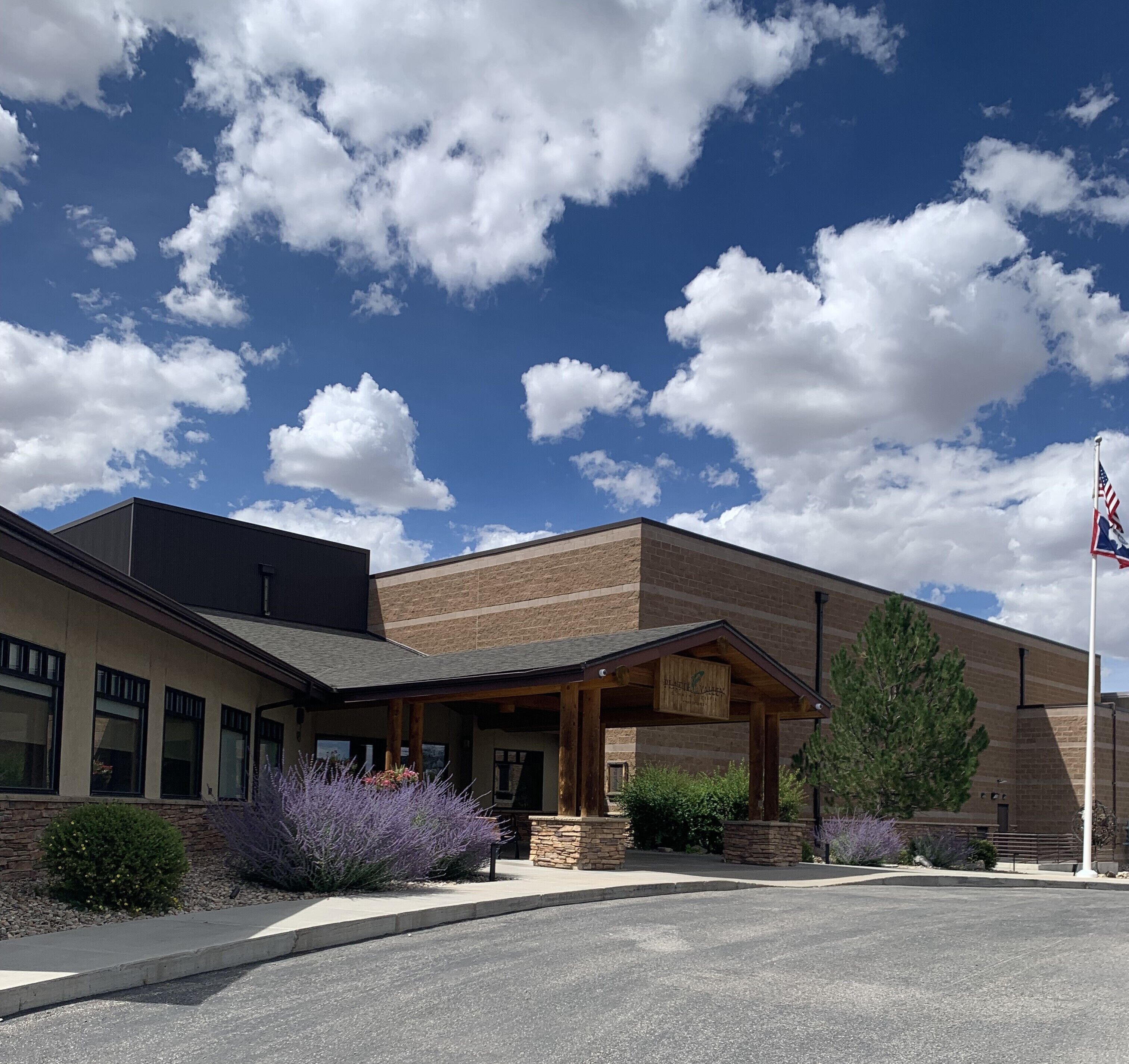 A building with a covered entrance, stone facade, and an American flag.