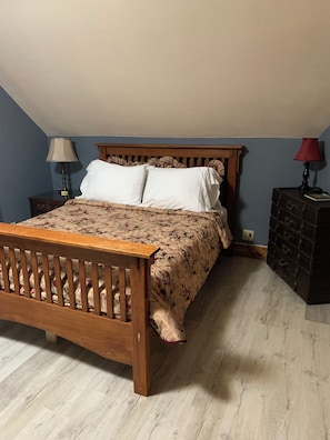 A bedroom with a wooden bed, a nightstand, a dresser, and two lamps.