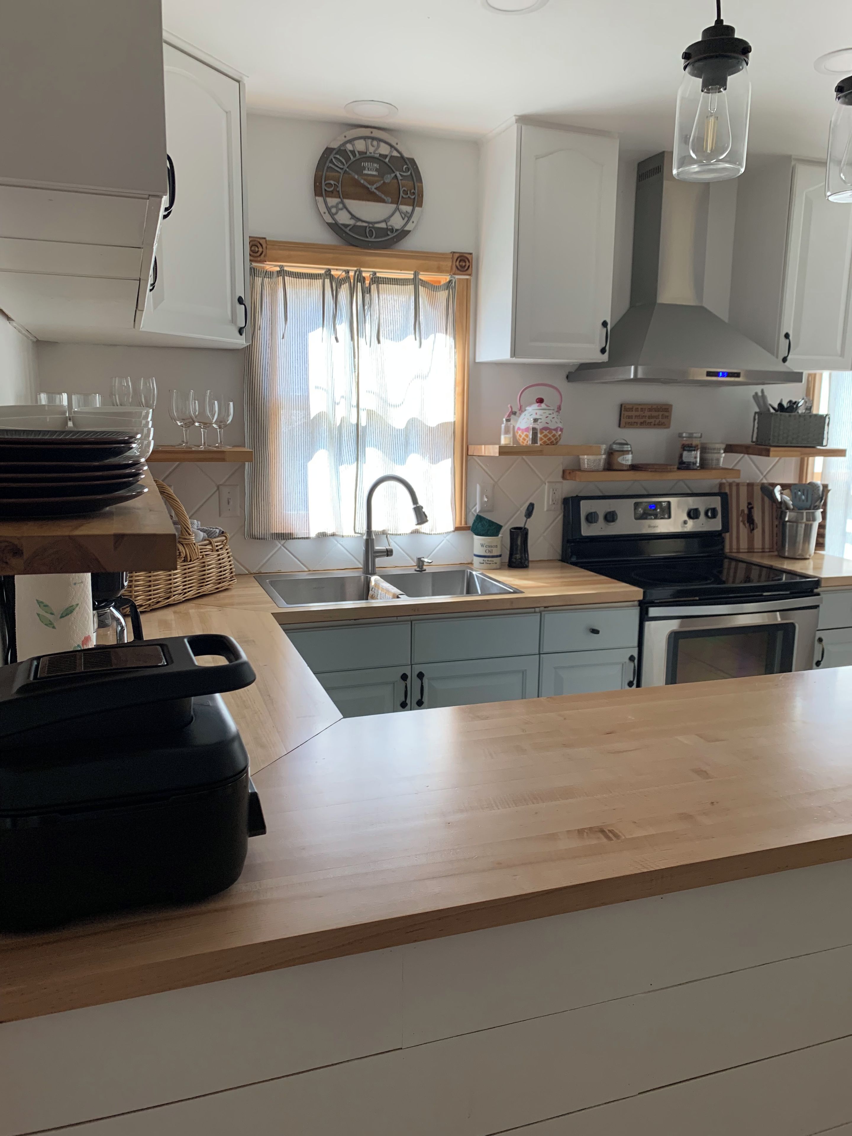 Une cuisine équipée d’un évier, d’une cuisinière et d’un plan de travail en bois.