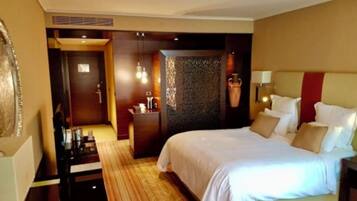 A hotel room with a large bed, a desk, and a seating area.