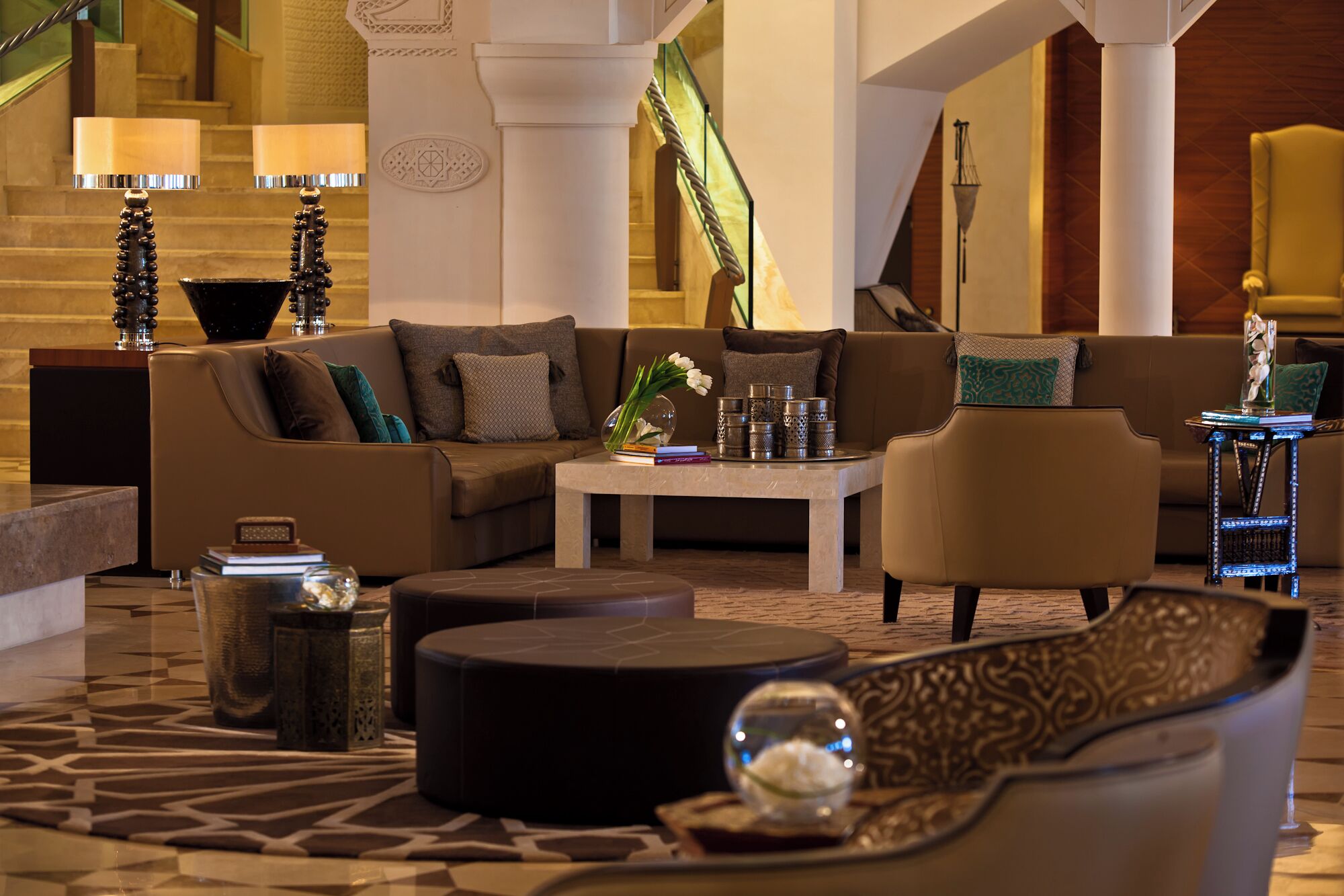 A modern hotel lobby with a sofa, armchair, coffee table, and decorative items.
