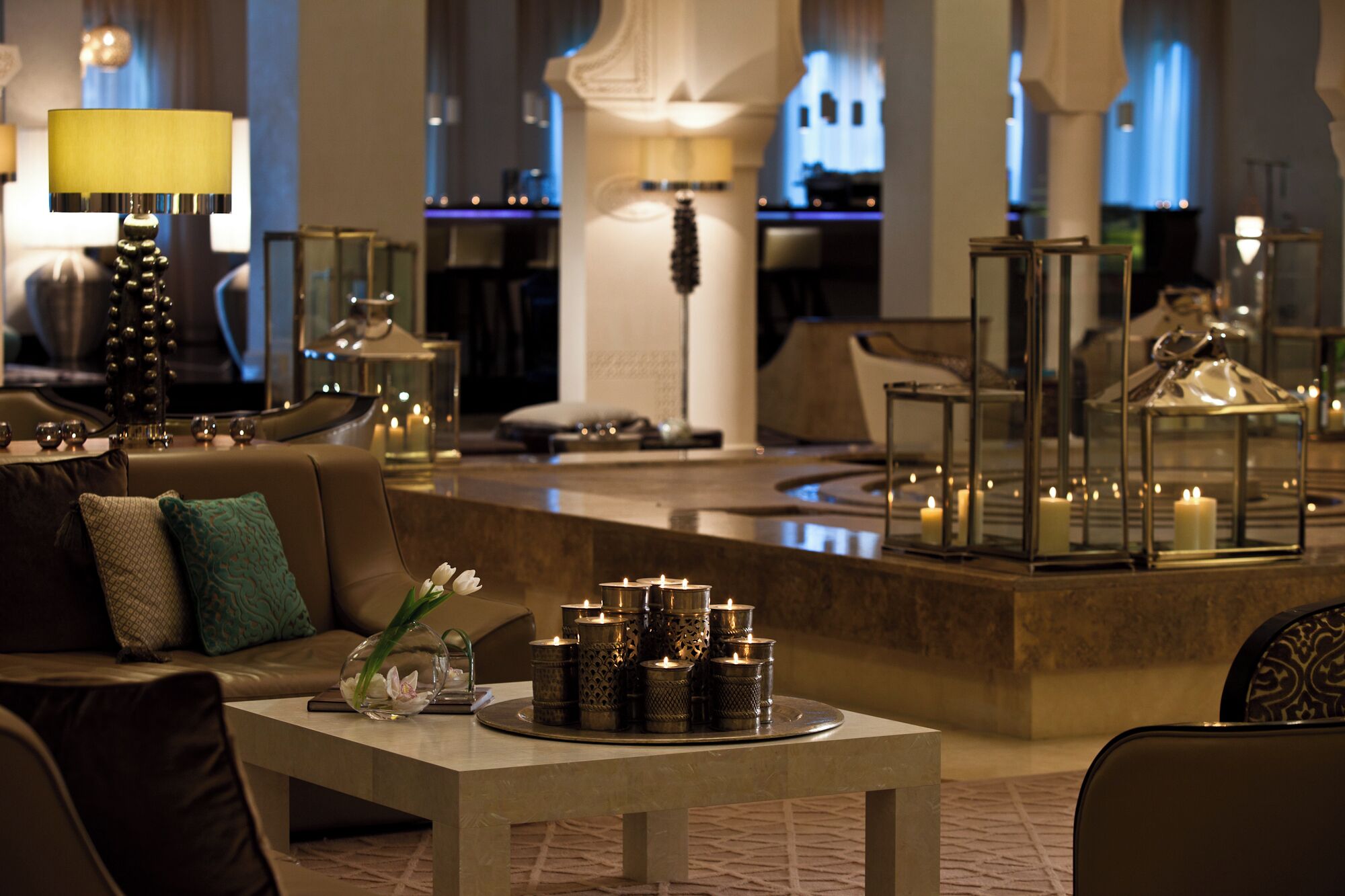 A modern hotel lobby with a seating area, a bar, and decorative lighting.