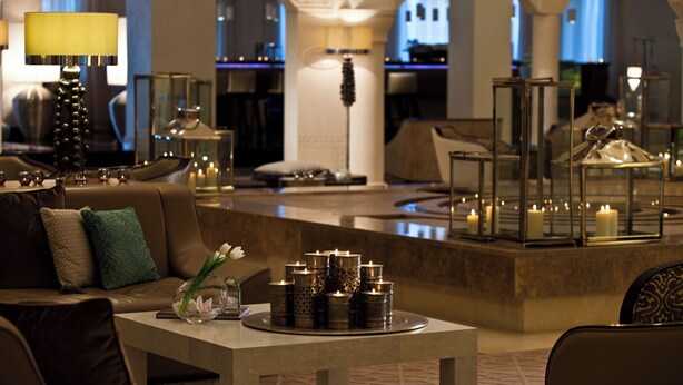 A modern hotel lobby with a seating area, a bar, and decorative lighting.