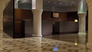 A reception area with a patterned floor, a reception desk, and a wall-mounted screen.