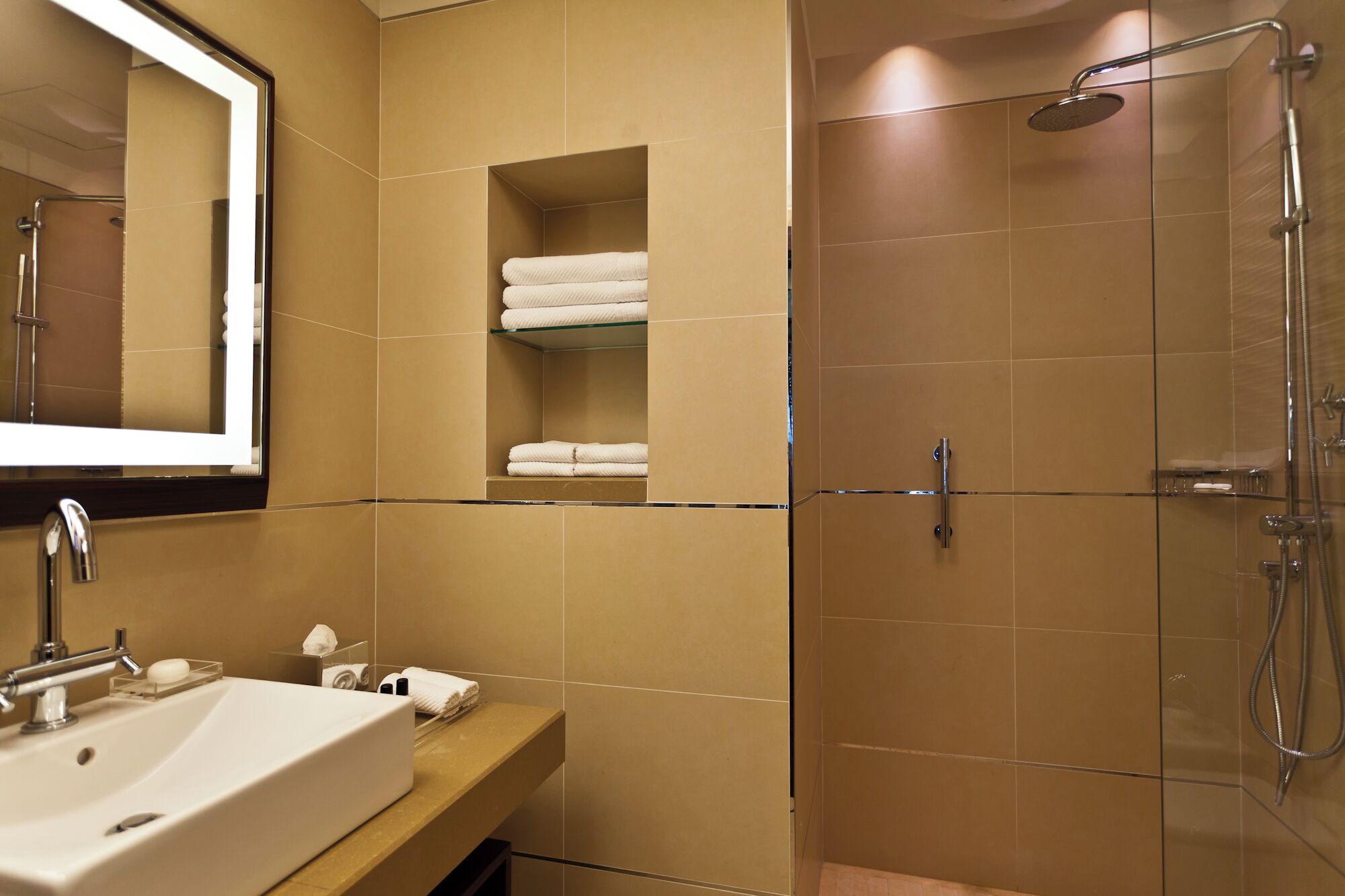 A bathroom with a sink, mirror, towel rack, and shower.