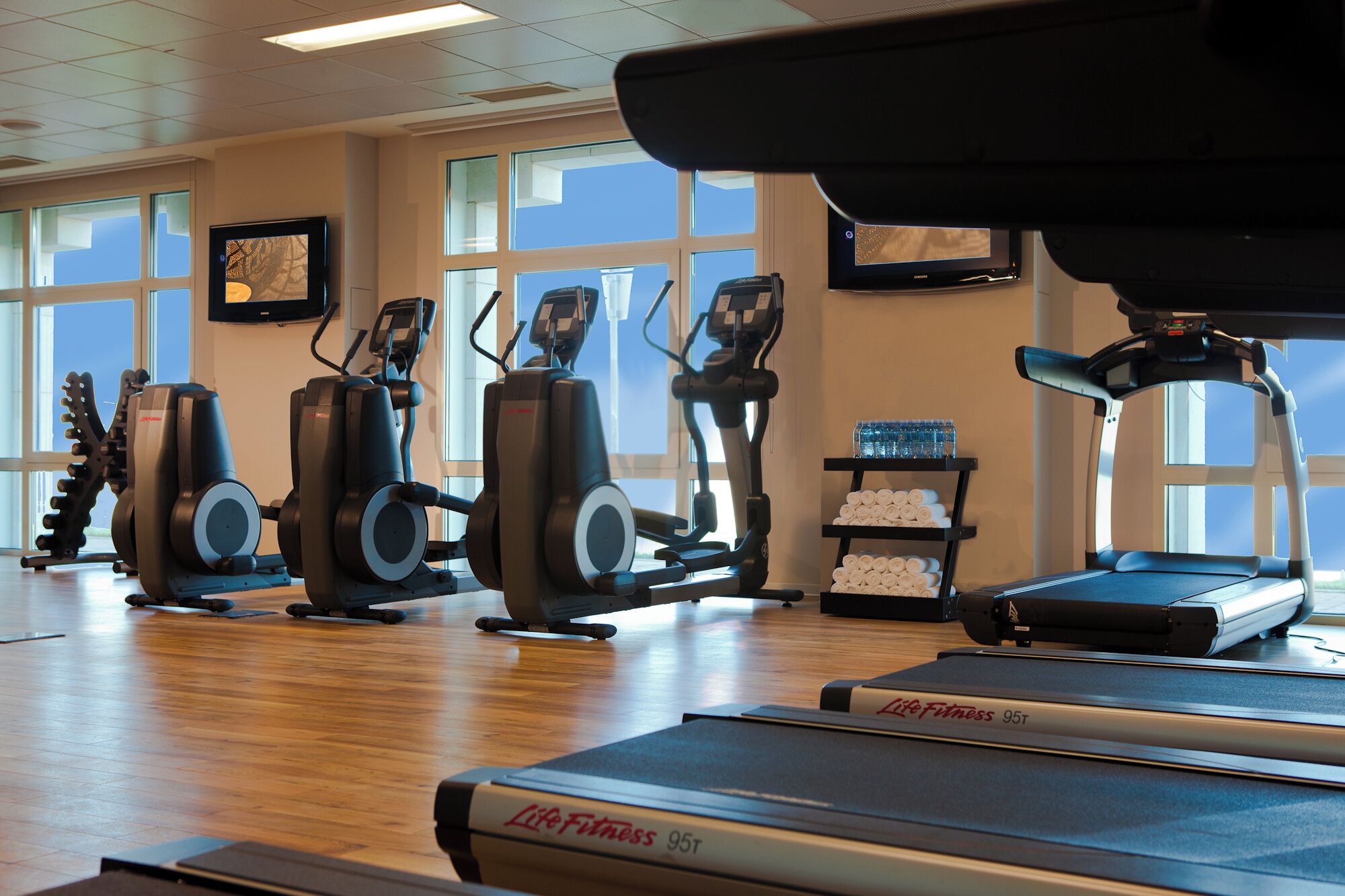 A gym with cardio equipment, a treadmill, and a water station.