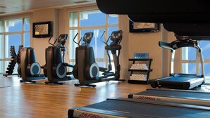 A gym with cardio equipment, a treadmill, and a water station.