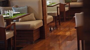 A restaurant interior with wooden flooring, cushioned seating, and tables with green placemats.