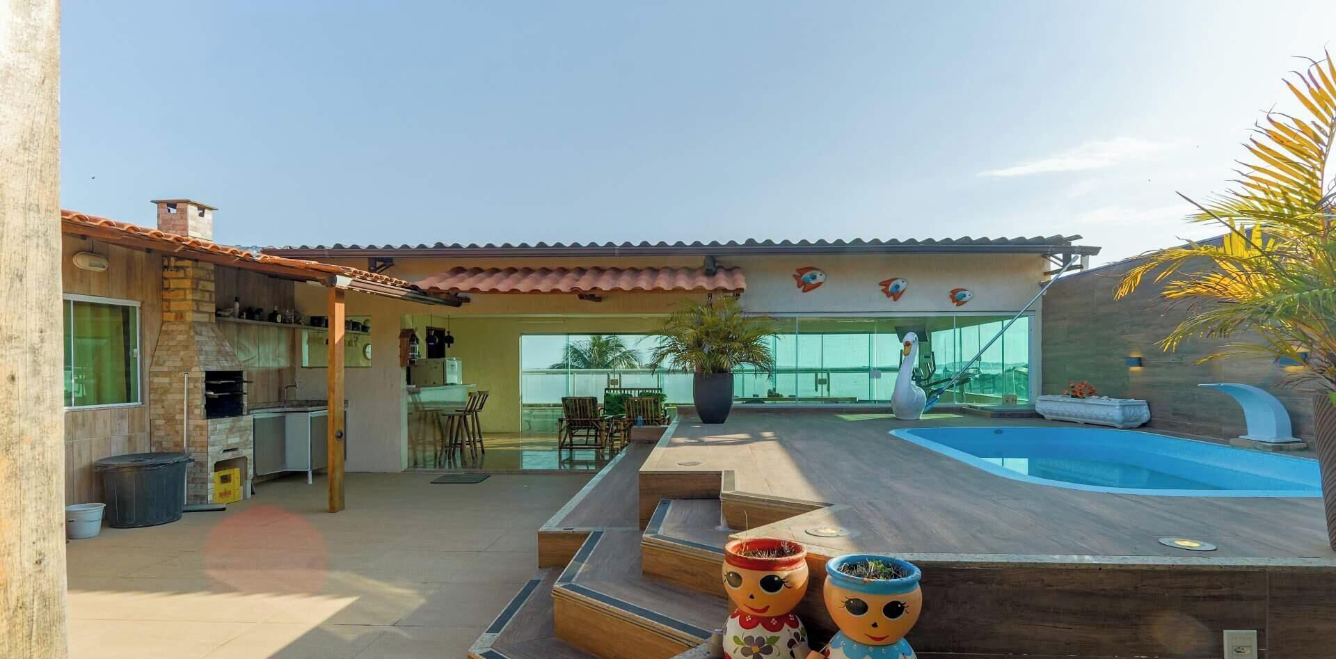 A residential property with a swimming pool, outdoor seating, and a kitchen area.