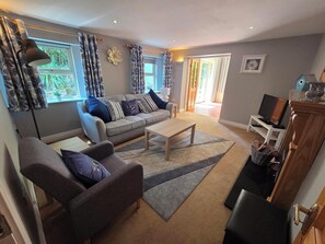 A living room with a sofa, armchairs, a coffee table, and a television.