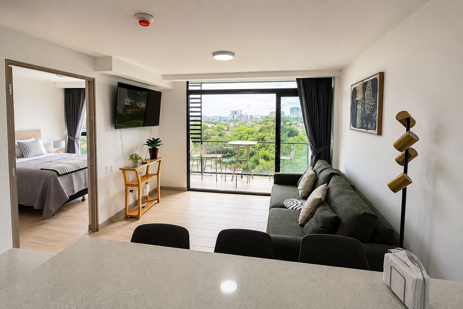 Una sala de estar moderna con un sofá, una mesa de comedor y un televisor montado en la pared.