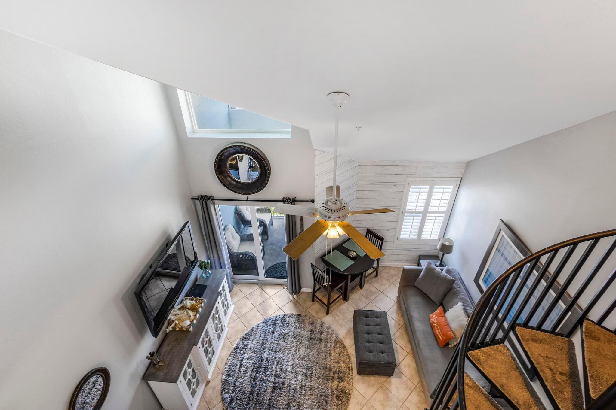 A spacious loft with a dining area, a staircase, and a large window providing natural light.