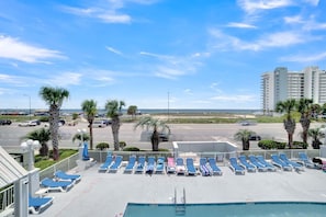 A rooftop pool area with blue lounge chairs and a view of the beach and ocean. - Grand Caribbean 423 (Orange Beach)