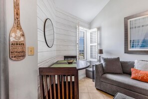 A cozy living room with a gray sofa, a wooden dining table, and a wall-mounted mirror. - Grand Caribbean 423 (Orange Beach)