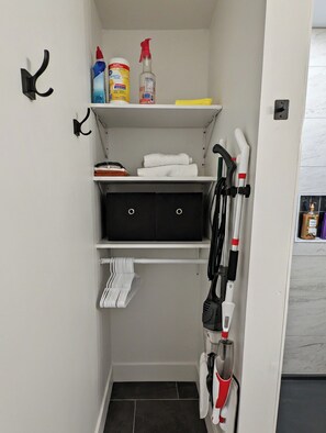 Ein kleiner Stauraum mit Regalen, einer Kleiderstange und einem Schrank.