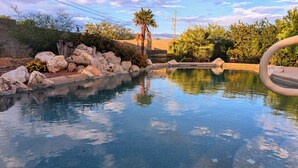 Uma piscina com água cristalina, cercada por pedras e plantas.