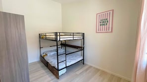 Uma cama de beliche em um quarto com piso claro e um quadro na parede.