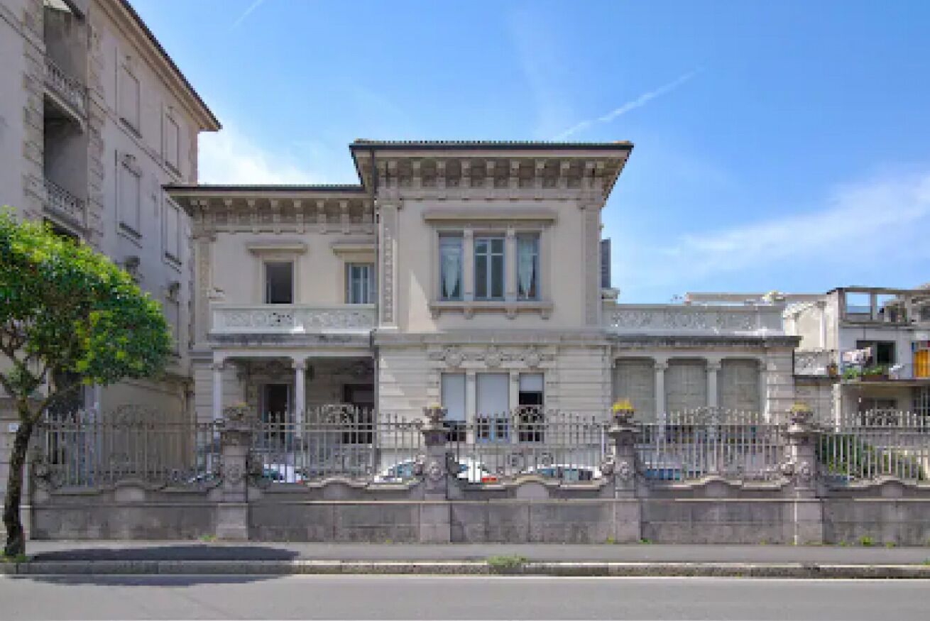 Un bâtiment de style classique, doté d’une façade symétrique, de grandes fenêtres et d’une grille en fer forgé décorative.