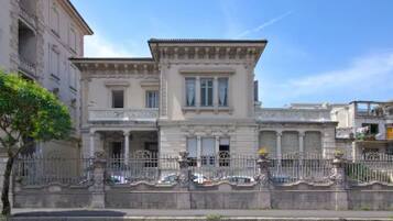 Un bâtiment de style classique, doté d’une façade symétrique, de grandes fenêtres et d’une grille en fer forgé décorative.