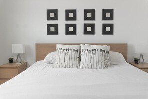 A bedroom with a large bed, two bedside tables, and a wall with six square frames. - Beauty apt Sunny Isles, 16th Floor. Great views! (Sunny Isles Beach)
