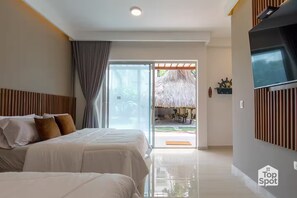 A modern hotel room with a bed, a TV, and a sliding glass door leading to an outdoor area with a thatched roof. - Luxury TopSpot Villa Para 16 a 150 mts de la Playa (Santa Marta)