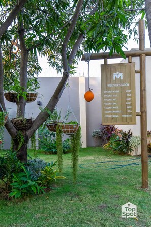 A garden with a tree, hanging planters, and a weather station sign. - Luxury TopSpot Villa Para 16 a 150 mts de la Playa (Santa Marta)
