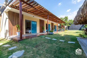 A modern house with a covered patio, a well-maintained lawn, and a thatched roof structure. - Luxury TopSpot Villa Para 16 a 150 mts de la Playa (Santa Marta)