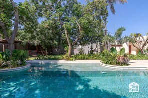 A pool surrounded by lush greenery and palm trees, with a clear blue sky above. - Luxury TopSpot Villa Para 16 a 150 mts de la Playa (Santa Marta)