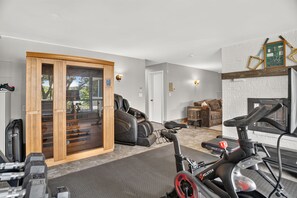 A home gym with exercise equipment, a sauna, and a fireplace. - Solara on the Lake (Plymouth)