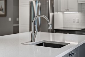 Una cocina moderna con un grifo de acero inoxidable, un lavamanos rectangular y una encimera con vetas.
