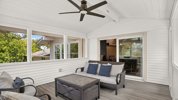 A covered porch with a ceiling fan, wicker furniture, and a view of the outdoors. - Solara on the Lake (Plymouth)