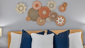 A bedroom with a wooden headboard, white bedding, and multiple decorative wall hangings. - Solara on the Lake (Plymouth)