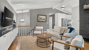 A modern living room with a flat-screen TV, a wooden coffee table, a sofa, and a patterned rug. - Solara on the Lake (Plymouth)