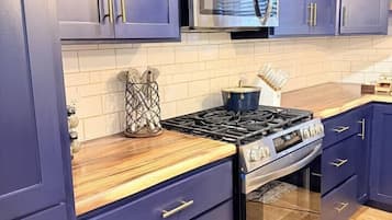 Una cucina con mobili scuri blu, un forno a microonde in acciaio inox, un piano cottura a gas e un forno integrato.