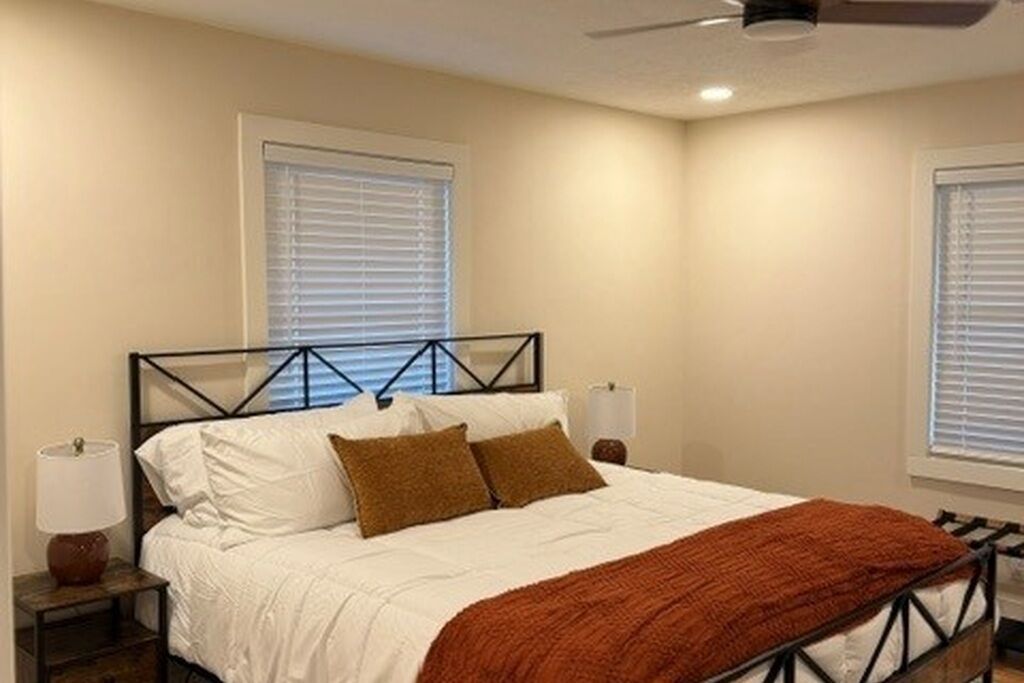 Una camera da letto con un letto, comodini e una ventola a soffitto.