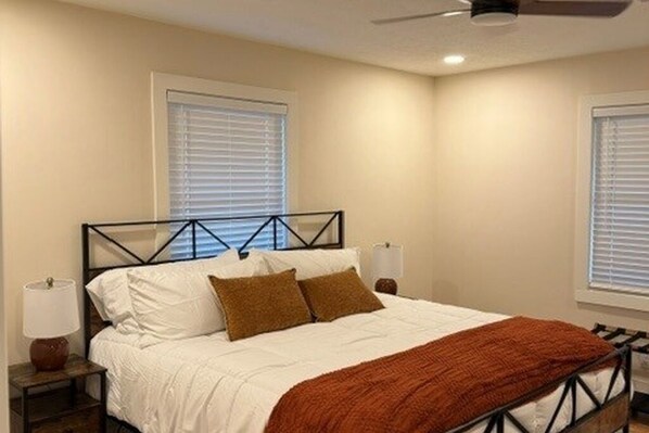 A bedroom with a bed, nightstands, and a ceiling fan.