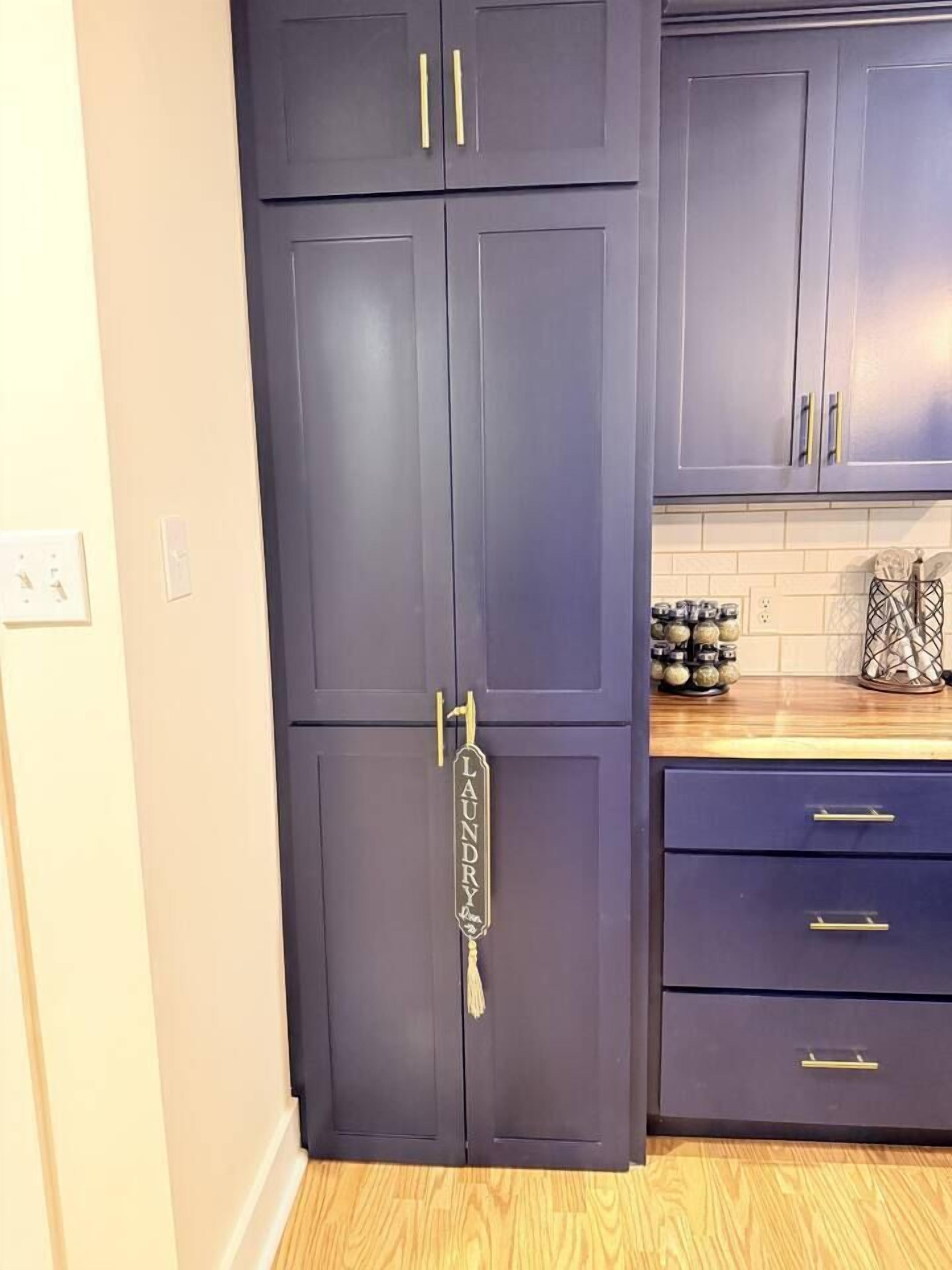 Una cucina con pensili scuri, un piano di lavoro in legno e un porta asciugamani a parete.